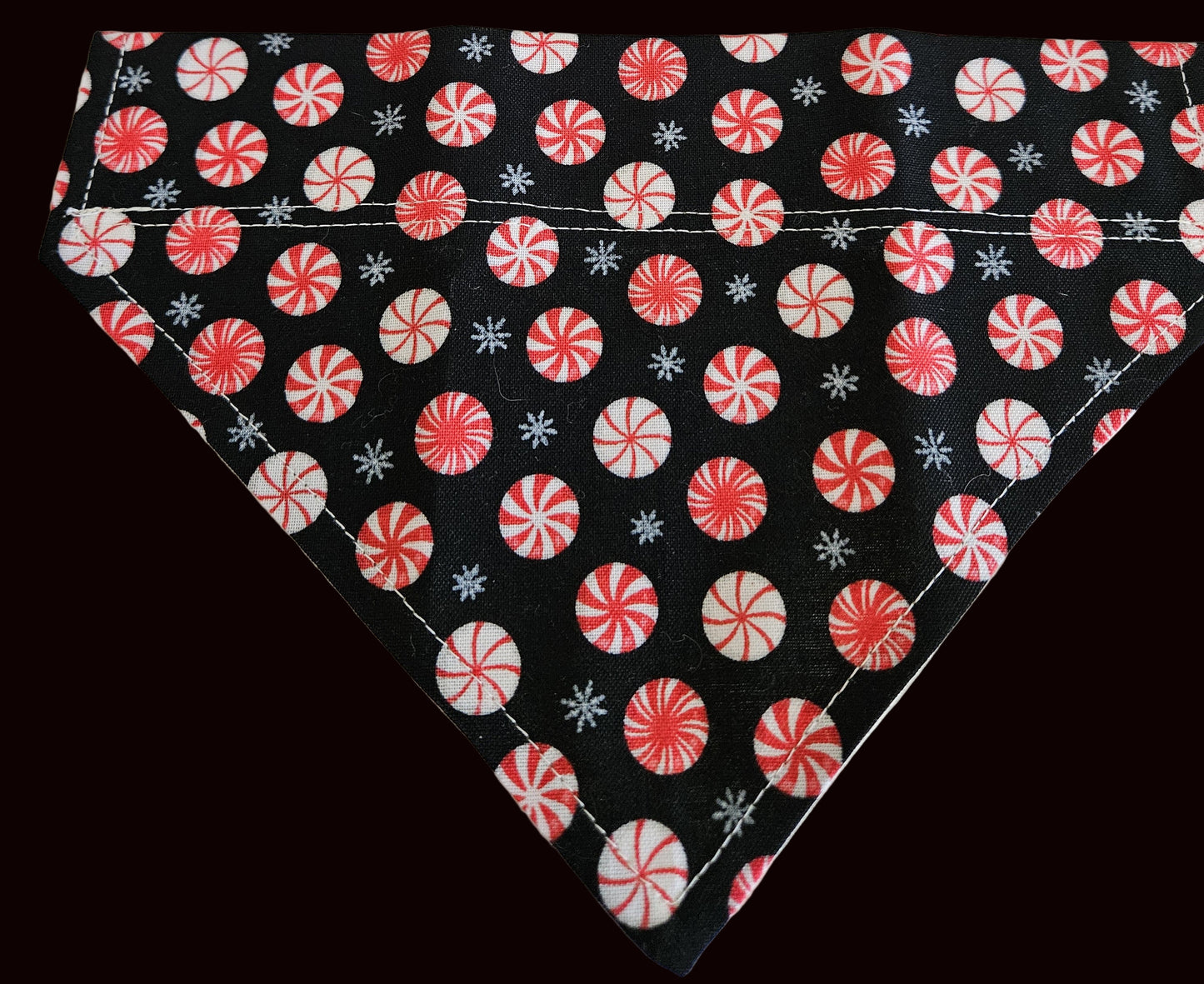 Fabric with red and white peppermint candy pattern on a black background